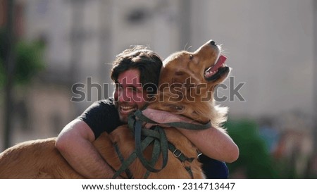 Happy dog owner laughing and smiling while hugging his Golden Retriever dog outside at park Royalty-Free Stock Photo #2314713447