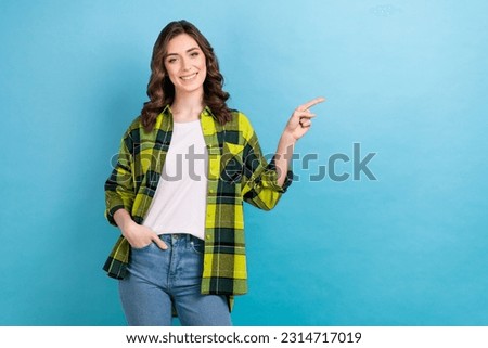 Photo of good mood cute woman dressed plaid shirt pointing finger empty space isolated blue color background