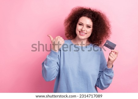 Photo of dreamy sweet lady dressed blue pullover holding bank card pointing thumb empty space isolated pink color background