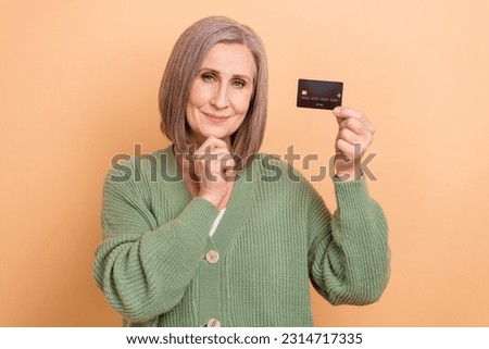 Photo of creative pretty person hand touch chin hold plastic debit card isolated on beige color background