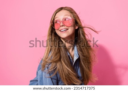 Photo portrait of pretty young teen girl fluttering hair look empty space dressed stylish denim outfit isolated on pink color background