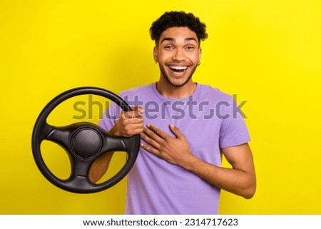 Photo of overjoyed cheerful young person hand touch chest laughing hold wheel isolated on yellow color background