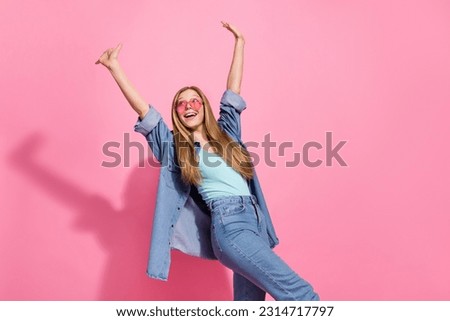 Photo portrait of pretty young teenager girl walk raise hands look empty space wear trendy jeans outfit isolated on pink color background