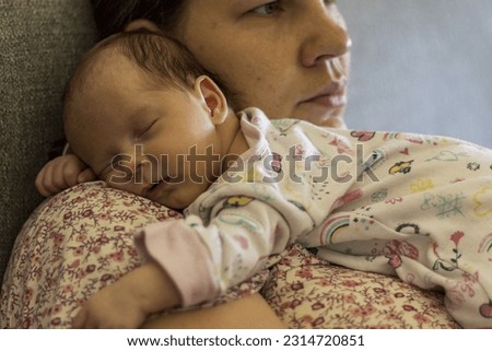 Abstract photo of a baby lying and sleeping on mom's shoulder. Baby, newborn, rest, mom, parent. Abstract photo with focus on a baby's face. Defocused background.