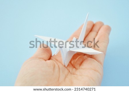 White paper origami bird on blue background