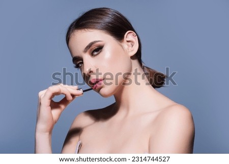 Studio portrait of beautiful woman with red lipstick. Beautiful young woman applying lipstick on her lips, isolated on studio background.