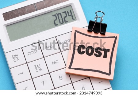 COST word on a small piece of paper placed on a calculator.