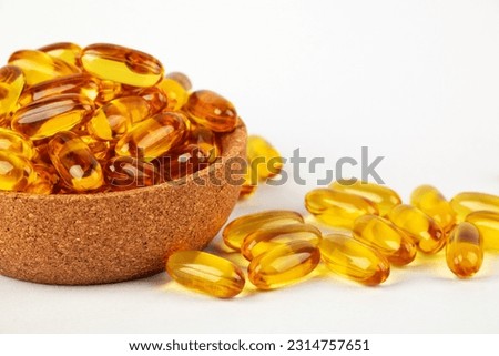 Cod liver oil omega 3 gel capsules in bowl on white background.