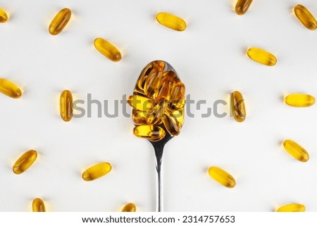 Omega 3 fish oil capsules on a spoon on a light background