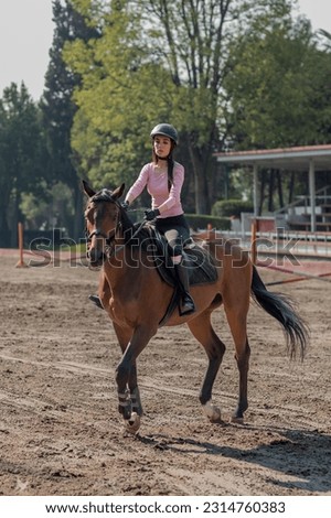 Vertical shot of a young woman riding a horse in an equestrian center