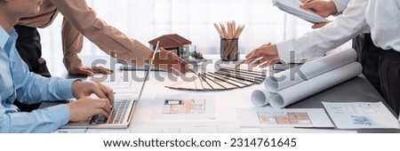 Group of interior designer team in meeting, discussing with engineer on interior design and planning for house project blueprint and model, choosing color sample and mood board materials. Insight Royalty-Free Stock Photo #2314761645