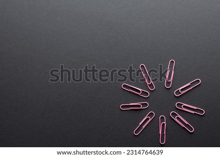 Close up of pink paper clips in circle and copy space on black background. School materials, organising, learning, school and education concept.