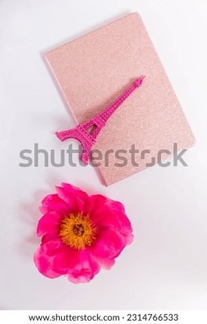 Pink figurine of the Eiffel Tower on the background of a notebook close-up.