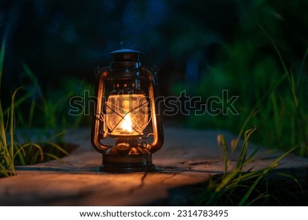 antique oil lamp on the old wooden floor in the forest at night camping atmosphere Royalty-Free Stock Photo #2314783495