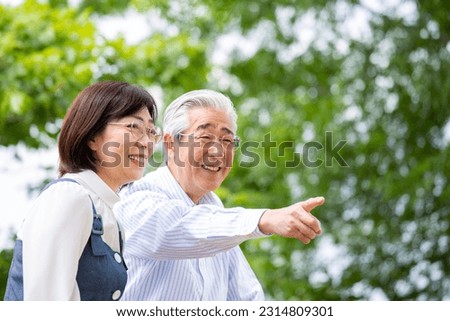 A Japanese middle-aged couple talking on a park bench, Royalty-Free Stock Photo #2314809301