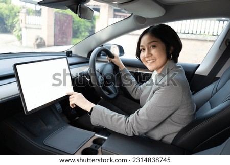 An Asian woman driving and using a touch screen GPS panel for navigation in a car.