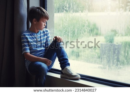 Boy child, rain and sad by window with thinking, mental health and space for mockup in home. Male kid, raining and think by glass with depression, mock up or bored with problem, winter or frustration