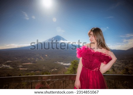Young girl wearing a red dress goes on a trip to take pictures and pose with Japan's Mount Fuji.
