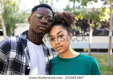 Portrait of African American young couple outdoors looking at camera with serious expression.