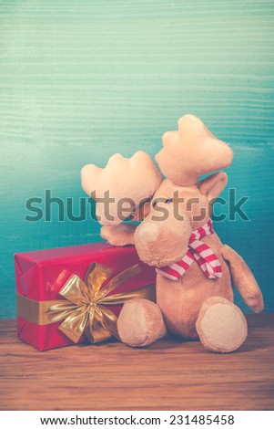 Cute Christmas reindeer with gift  in vintage style on wood