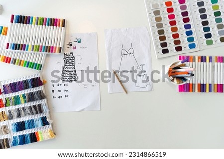 Fashion designer room. Pattern for cloth, silk thread color sample catalog, multi colored magic pens and sketching place on a large table. Top View
