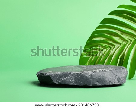 Stone podium product with tropical leaves on green background