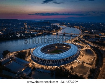 Budapest, Hungary - Aerial skyline of Budapest at dusk, including illuminated National Athletics Centre, Rakoczi bridge over River Danube and MOL Campus building at background with colorful sunset sky Royalty-Free Stock Photo #2314873799
