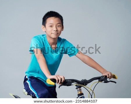 Studio shot of a little boy with bicycle on grey background