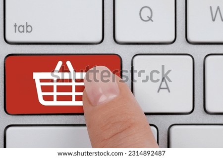 Online store purchase. Woman pressing red button with shopping basket on computer keyboard, top view