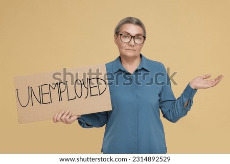 Confused senior woman holding cardboard sign with word Unemployed on beige background