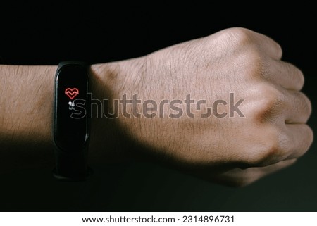 A smartwatch in the hand of men is showing heart rate. Isolated black background. Royalty-Free Stock Photo #2314896731