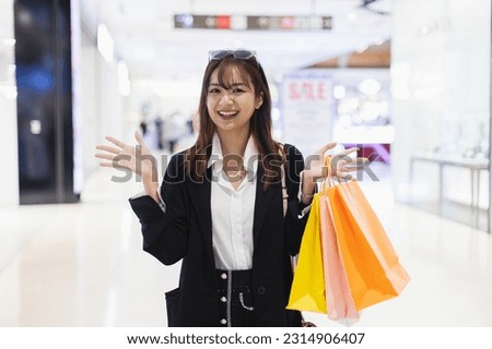 Happy smile woman wear black suit cheerful holding shopping bag colorful in supermarket. Female relaxation at shopping mall in holiday.
