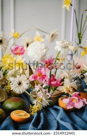 Summer composition of garden flowers. Beautiful bouquet in vase, orange, pear, pomelo, grapefruit on table. Home interior with decor elements. Festive decorated with flowers, fruits, greenery, candles