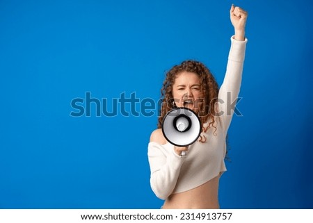 Young smiling expressive caucasian woman shout in megaphone against blue background Royalty-Free Stock Photo #2314913757
