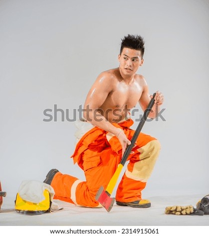 Professional firefighter is sitting in a prepared position ready to save lives while firmly holding an iron axe.