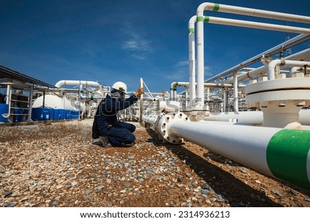 Production operator opening ball valve at pipeline oil and gas wellhead remote platform to control gases and crude oil process petroleum industry. Royalty-Free Stock Photo #2314936213