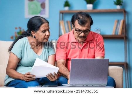 Indian senior couple discussing by checking documents or bills by using laptop at home - concept of technology, financial planning and relationship bonding Royalty-Free Stock Photo #2314936551