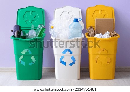Containers with different types of garbage near lilac wall. Recycling concept