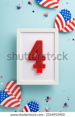 Unity Day celebration. Vertical top view of symbolic adornments: number four cake candle, hearts decorated with American flag pattern, confetti on pastel blue backdrop