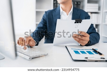 Asian businessman working at office with laptop and documents on table.