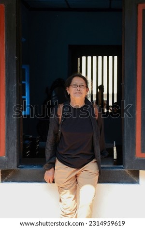 Asian woman standing in front of black old wooden window frame in a China town