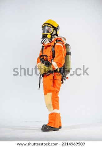 Side view of firefighter wearing yellow hard hat standing holding fire hose with both hands and looking to the top on white background.