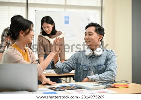 A professional Asian male developer giving high five to his colleague while brainstorming and planning a new project with his team in the meeting room together. Tech startup, Tech company concepts