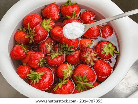 Rinsing fresh strawberry fruit in water with the addition of baking soda Royalty-Free Stock Photo #2314987355