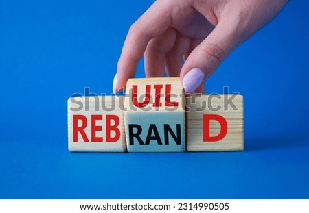 Rebuild and Rebrand symbol. Businessman hand turns wooden cubes and changes the word to Rebrand to Rebuild. Beautiful blue background. Rebuild Rebrand and Business concept. Copy space