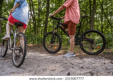 Senior man and his adult daughter standing with bicycle in the grass at the summer