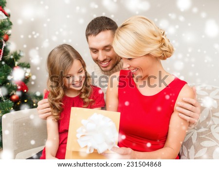 christmas, holidays, happiness and people concept - smiling family looking into open gift box at home