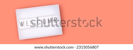 Banner with word Welcome. White lightbox with letters on a coral colored background. Place for text.