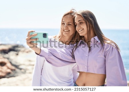 Two women mother and daughter make selfie by smartphone at seaside