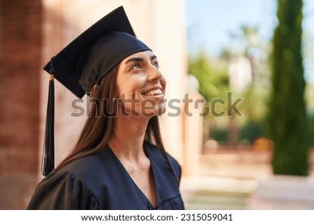 Young hispanic woman wearing graduated uniform looking to the sky at university Royalty-Free Stock Photo #2315059041